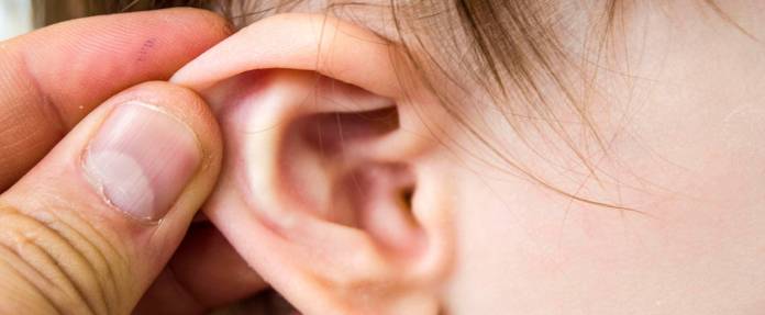 Mann fasst Kind ans Ohr, dass entzündet ist