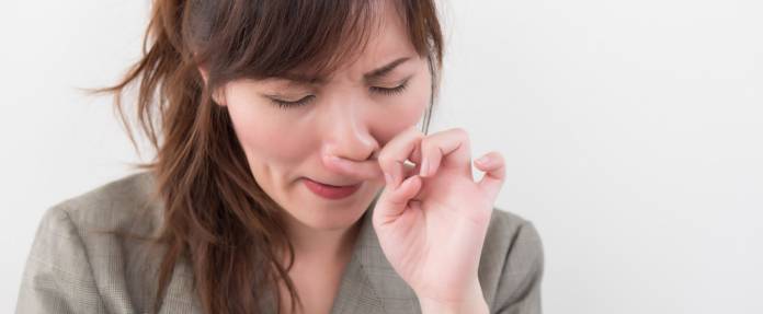 Frau reibt sich die Nase