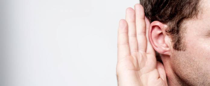 Mann fasst sich hinters Ohr, um besser zu hören