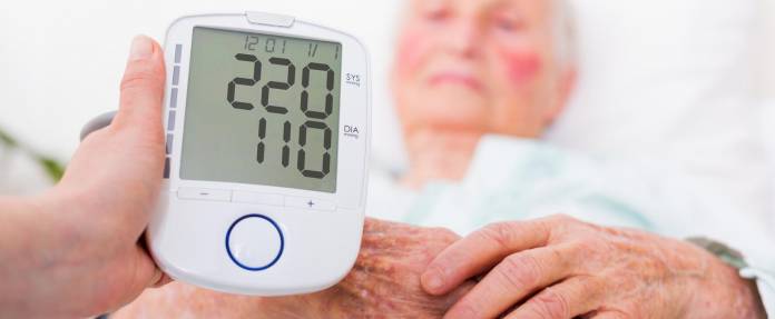 Extrem hoher Blutdruck einer älteren Frau wird auf Messgerät angezeigt
