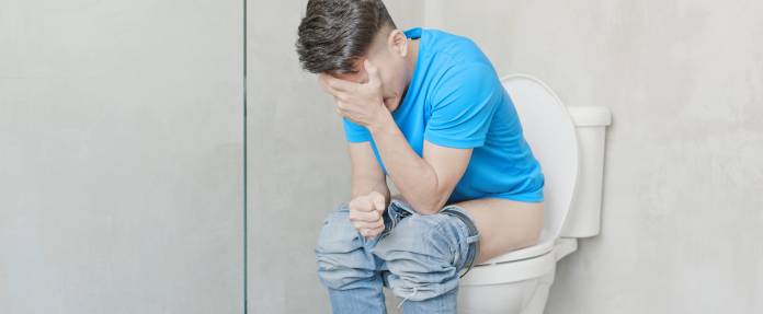 Mann mit Schmerzen beim Wasserlassen auf Toilette