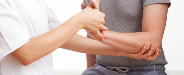 Physiotherapeutin mobilisiert Arm und Hand eines Patienten