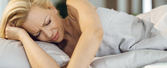 Frau, die im Bett liegt, hat Schmerzen