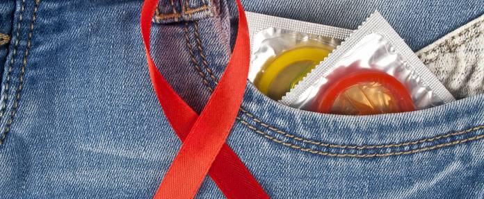 Kondome und Schleife der Aidshilfe an Jeans-Hosentasche