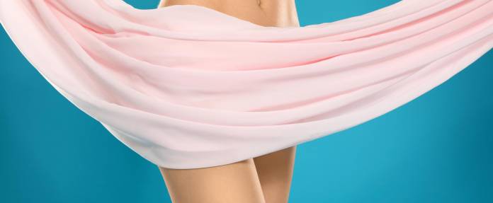 Junge Frau verhüllt Intimbereich mit rosa Tuch