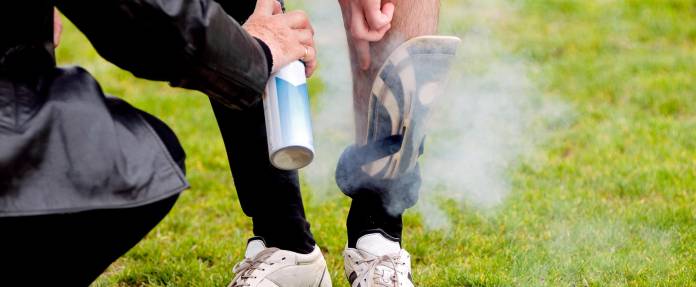 Fußballspieler wird mit Eisspray an Schienbein behandelt