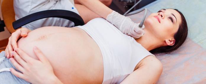 Junge schwangere Frau bei Ultraschalluntersuchung der Schilddrüse