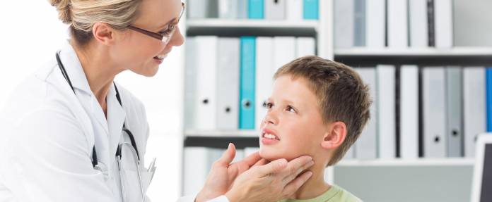 Ärztin untersucht die Schilddrüse eines Jungen