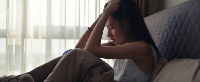 Junge asiatische Frau mit Depressionen im Bett liegend