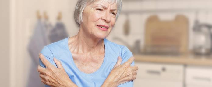Ältere Frau mit Schmerzen fasst sich an den Oberarmen