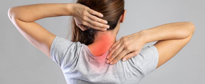 Junge Frau mit Schmerzen im Nacken bzw. an der Halswirbelsäule