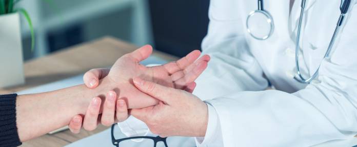 Arzt untersucht Hand einer Patientin