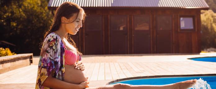 Schwangere Frau planscht mit den Füßen in einem Pool