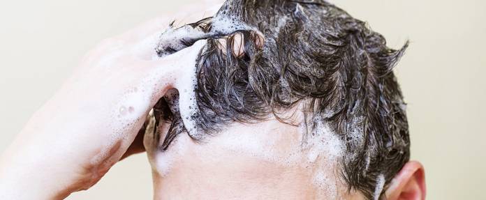 Mann wäscht sich die Haare mit Shampoo