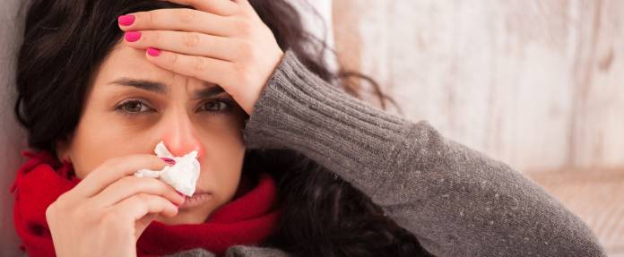 Frau mit Sinusitis und Kopfschmerzen im Bett