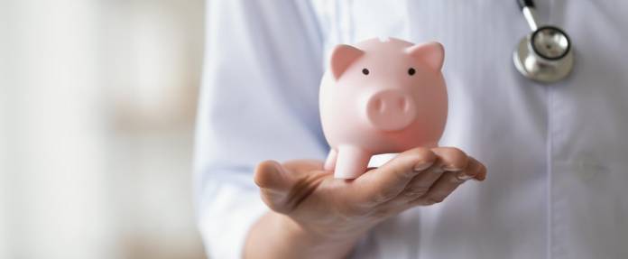 Junge Ärztin mit Sparschwein auf der Hand