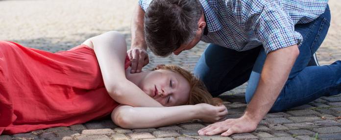 Mann fühlt Puls bei ohnmächtiger Frau 