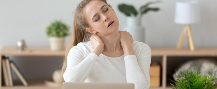 Junge Frau, die am Laptop arbeitet, hat Schmerzen im Nacken