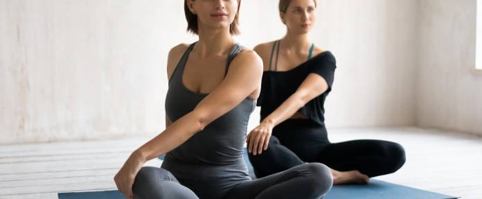 Zwei Frauen bei Yogaübungen auf der Matte sitzend