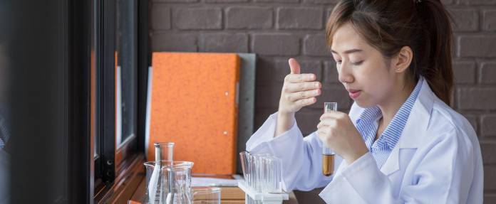 Asiatin riecht im Chemielabor an einem Reagenzglas