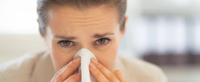 Frau putzt sich die Nase mit Taschentuch