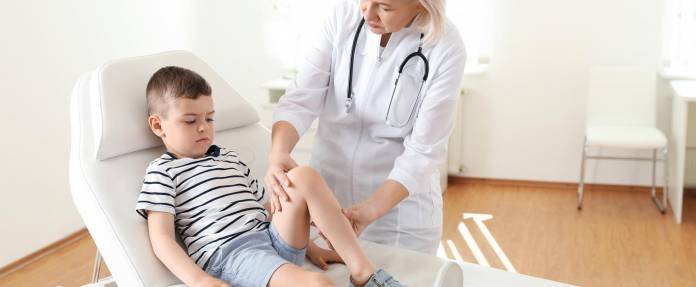 Kind bei Behandlung der Beine durch eine Ärztin