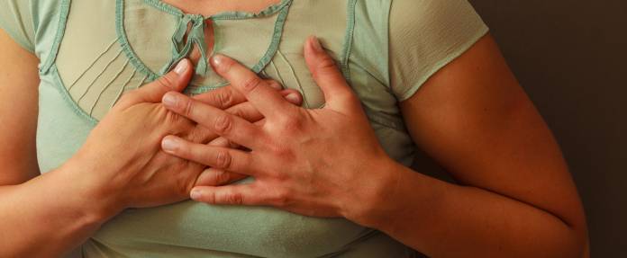 Frau hält sich schmerzende Brust