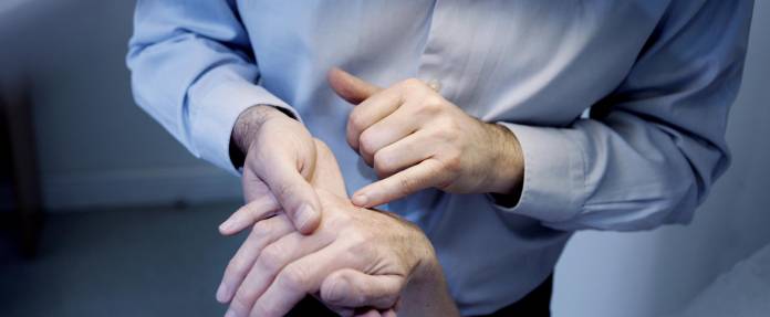 Hautarzt untersucht Handrücken einer Frau