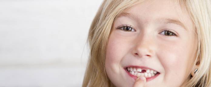 Junges Mädchen zeigt auf Ihre Zahnlücke im Mund