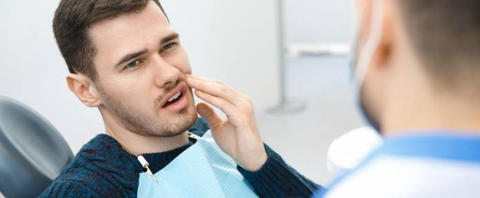 Mann mit Zahnschmerzen beim Zahnarzt