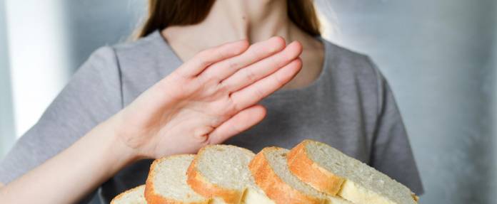 Frau zeigt mit einer ablehnenden Handbewegung an, dass Sie kein Weißbrot verträgt