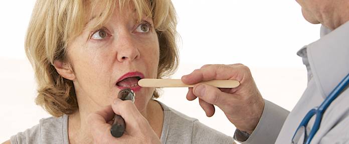 Arzt untersucht Zunge und Hals einer älteren Frau