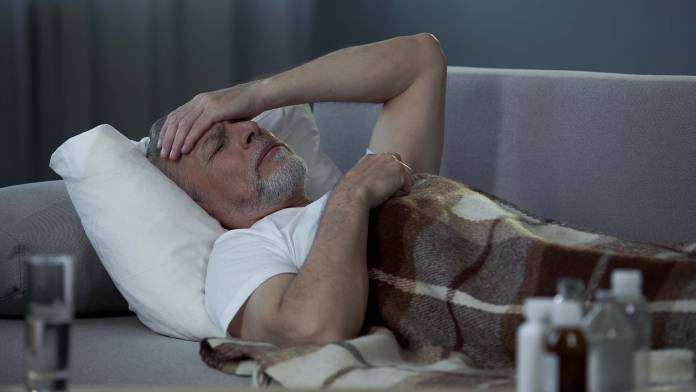 Älterer Mann mit Kopfschmerzen liegend auf der Couch