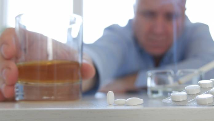 Mann trinkt Alkohol und nimmt Tabletten