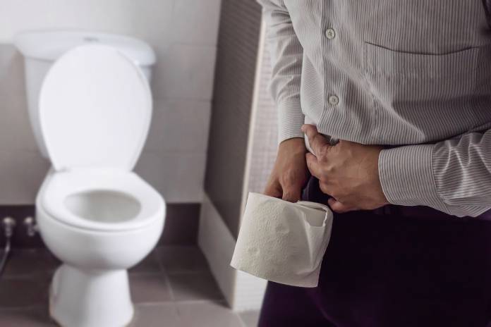 Mann mit Magenbeschwerden vor Toilette